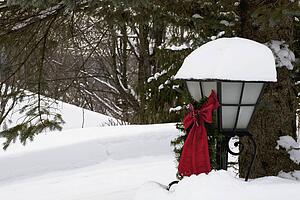 Christmas decorations attached to a street lamp heavily covered in snow