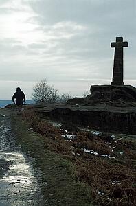 Baslow, Derbyshire, England, United Kingdom; Person walking by a cross monument in a national park