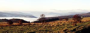 View across fields to a mist covered valley
