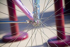 Close up of spokes on a pink bicycle, 