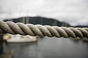Close up thick rope, with fishing boats in background