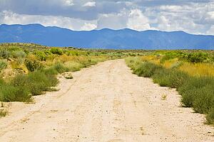 New Mexico, USA; Desert trail with mountains in the distance
