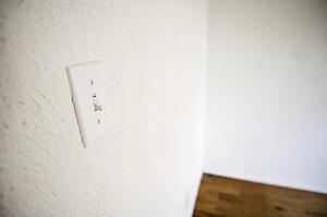 Empty room with white walls, white lightswitch and a wooden floor