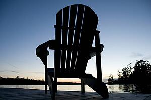 Lake of the Woods, Ontario, Canada; Empty deck chair on a pier next to a lake