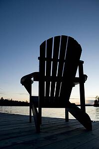 Lake of the Woods, Ontario, Canada; Empty deck chair on a pier next to a lake
