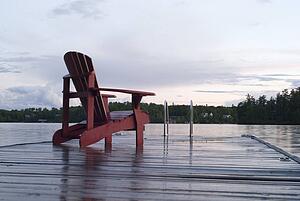 Lake of the Woods, Ontario, Canada; Empty deck chair on a pier next to a lake