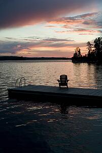 Lake of the Woods, Ontario, Canada; Empty deck chair on a pier next to a lake