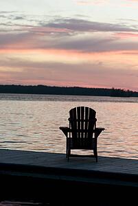 Lake of the Woods, Ontario, Canada; Empty deck chair on a pier next to a lake