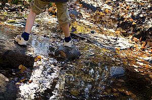 Low section of boy stepping on stones