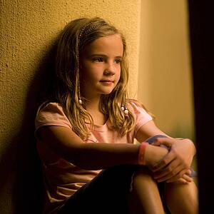 Girl sitting by a wall