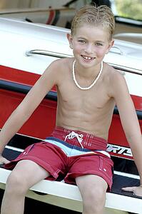 Boy sitting on boat wearing bathing suit