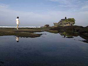 Tanah Lot Sea Temple, Bali, Indonesia; Woman walking along the shore