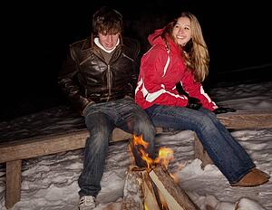 Couple sitting by a fire in the snow