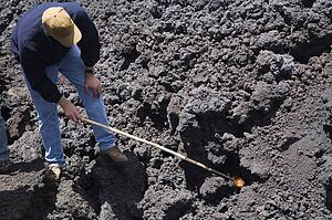 Antigua, Guatemala, Central America; Man with a stick pointed at lava