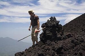 Man on a hill; Man with a stick looking down a hill