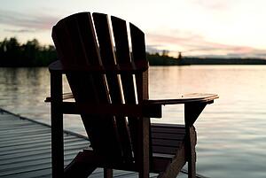 Lake of the Woods, Ontario, Canada; Empty deck chair on a pier next to a lake