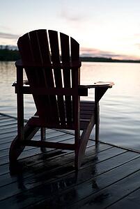 Lake of the Woods, Ontario, Canada; Empty deck chair on a pier next to a lake