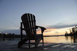 Lake of the Woods, Ontario, Canada; Empty deck chair on a pier next to a lake