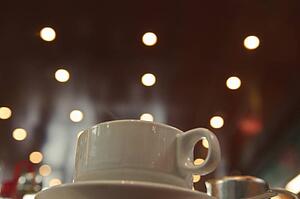 Cup of coffee; Cup sitting on a saucer with lights in the background 