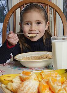 Young girl eating cereal at breakfast table