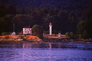 Small lighthouse with trees and hill behind