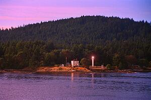Small lighthouse with trees and hill behind