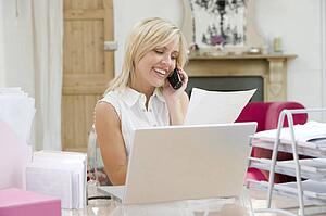 Woman using laptop and talking on phone