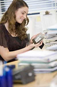 Woman sitting at her desk, looking at a photo of her family