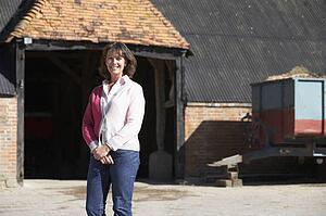 Farmer's Wife Standing In Front Of Farm Buildings