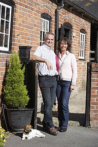 Farmer And Wife Standing In Front Of Farmhouse