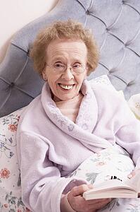 Senior Woman Relaxing In Bed With Book