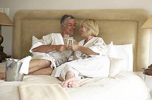 Middle Aged Couple Enjoying Champagne In Bedroom