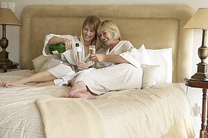 Two Women Enjoying Champagne In Bedroom