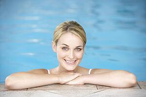 Young Woman Resting On Edge Of Swimming Pool