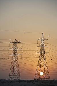 Electricity Pylons Silhouetted At Sunset
