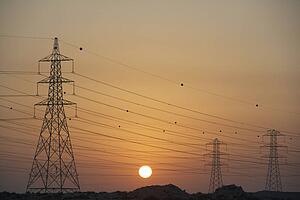 Electricity Pylons Silhouetted At Sunset