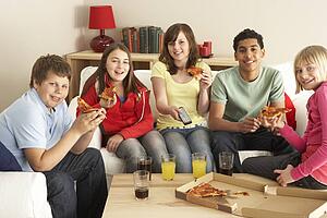 Group Of Children Eating Pizza Watching TV