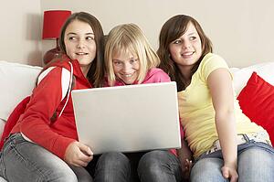 Group Of Three Girls Using Laptop At Home