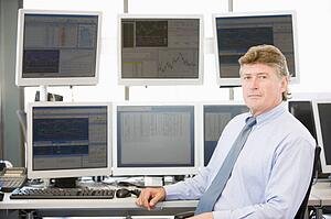 Portrait Of Stock Trader In Front Of Computer Monitors