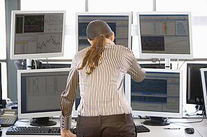 Stock Trader Looking At Multiple Monitors