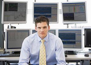 Portrait Of Stock Trader In Front Of Computer Monitors