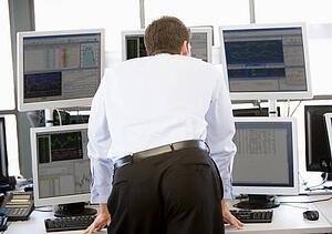 Stock Trader Looking At Multiple Monitors