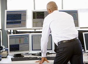 Stock Trader Looking At Multiple Monitors