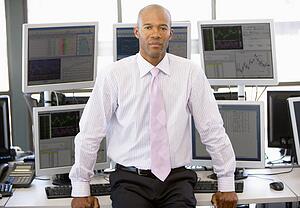 Portrait Of Stock Trader In Front Of Computer Monitors