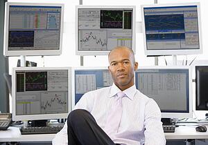 Portrait Of Stock Trader In Front Of Computer Monitors