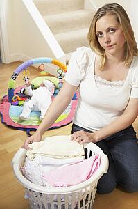 Mother Folding Baby Clothes At Home