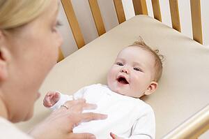 Mother Playing With Baby In Cot