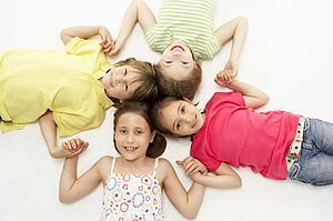 Circle of four young friends smiling and holding hands