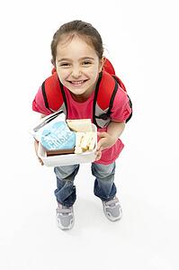 Studio Portrait of Smiling Girl Holding Lunchbox