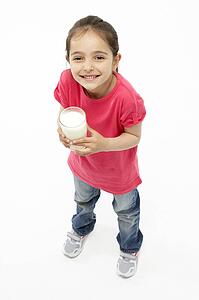 Studio Portrait of Smiling Girl Holding Glass of Milk